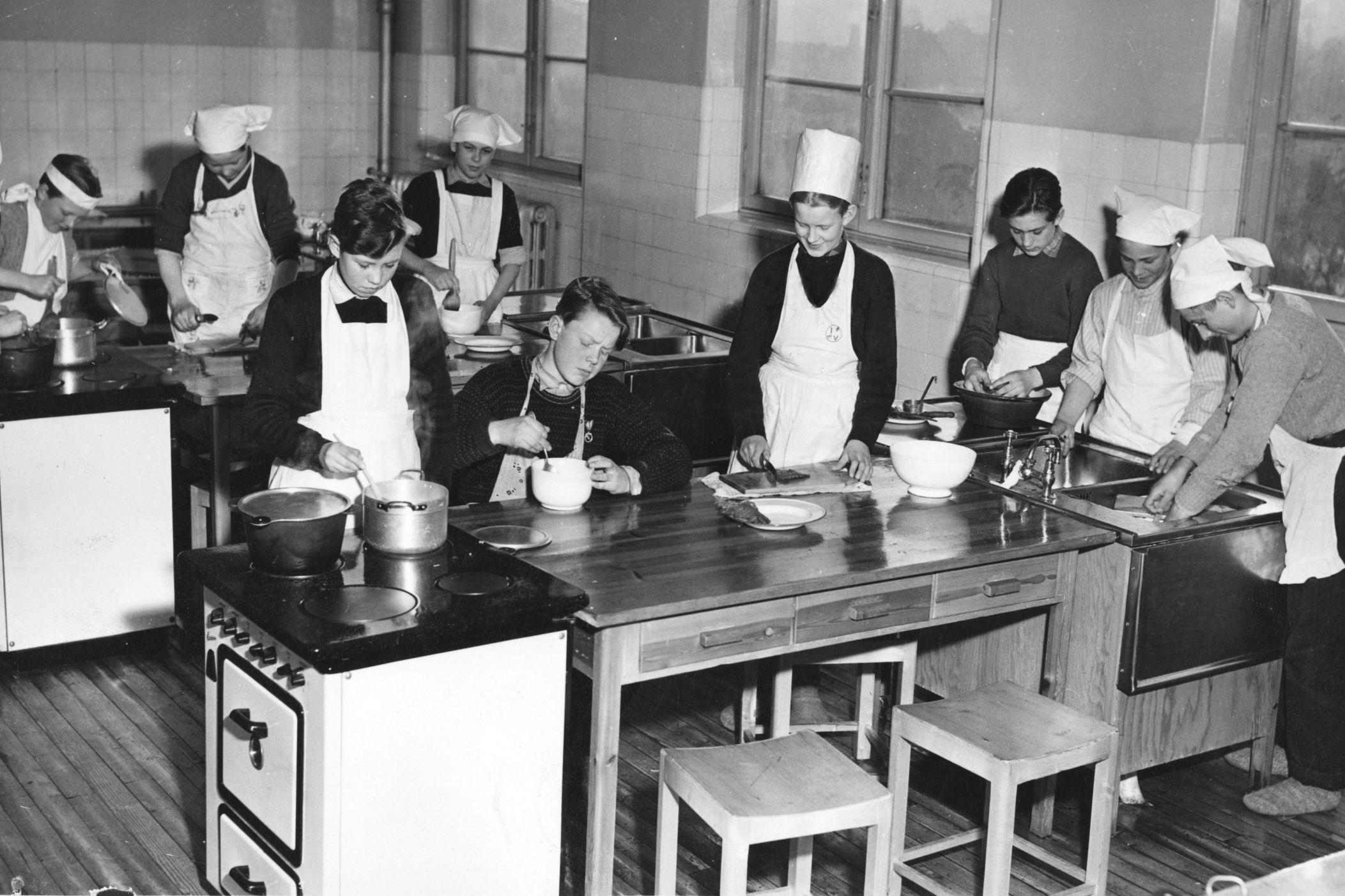 SKOLEKJØKKEN 1952: Elever i en gutteklasse på Sagene folkeskole har heimkunnskap. Noen står bak kjelene, mens andre kutter eller vasker opp. Foto: NTB arkiv/Scanpix