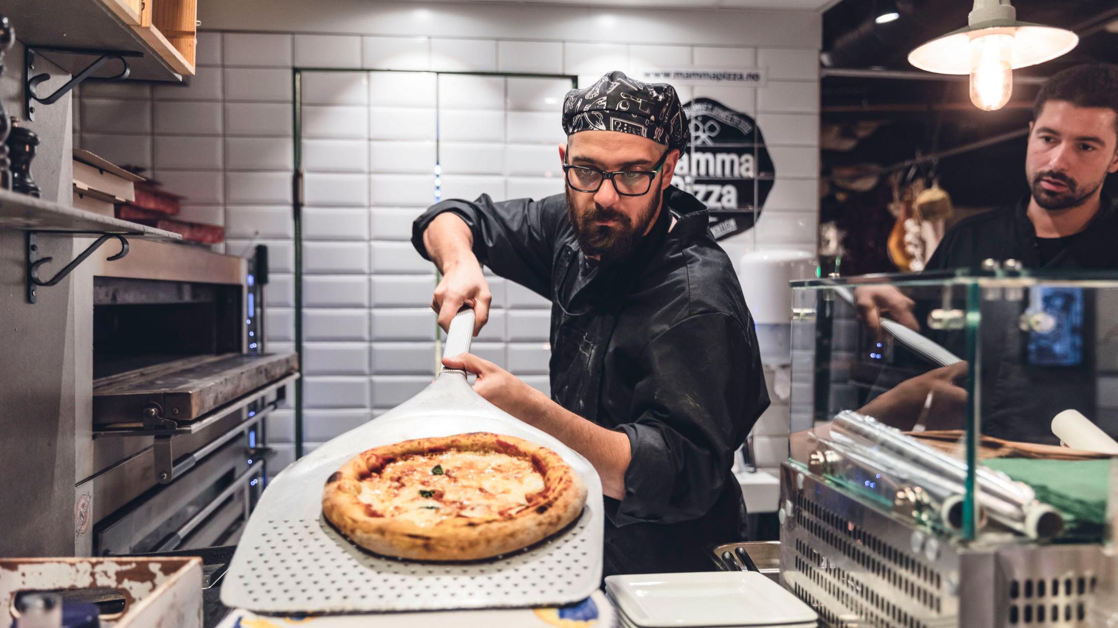 ALLORA: På Mamma Pizza tar Luca Furio Paolieri (til venstre) ut en rykende varm pizza av ovnen, mens Luca Zaninni følger med. Foto: Krister Sørbø/VG