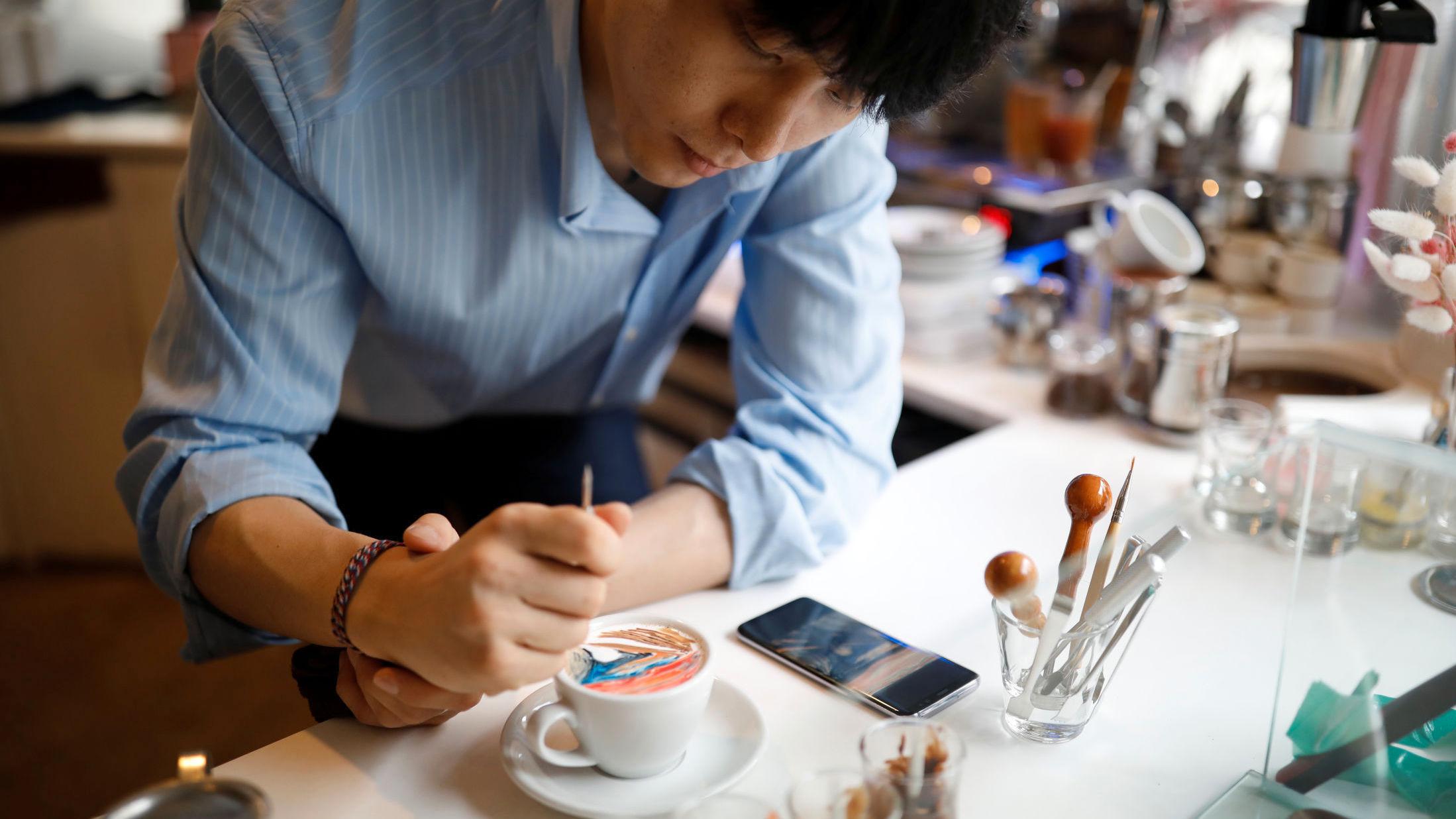 PRESISJON: Kaffeeksperten bruker pensler med matfarge for å få motivene på plass i skummet. Foto: Kim Hong-Ji/Reuters