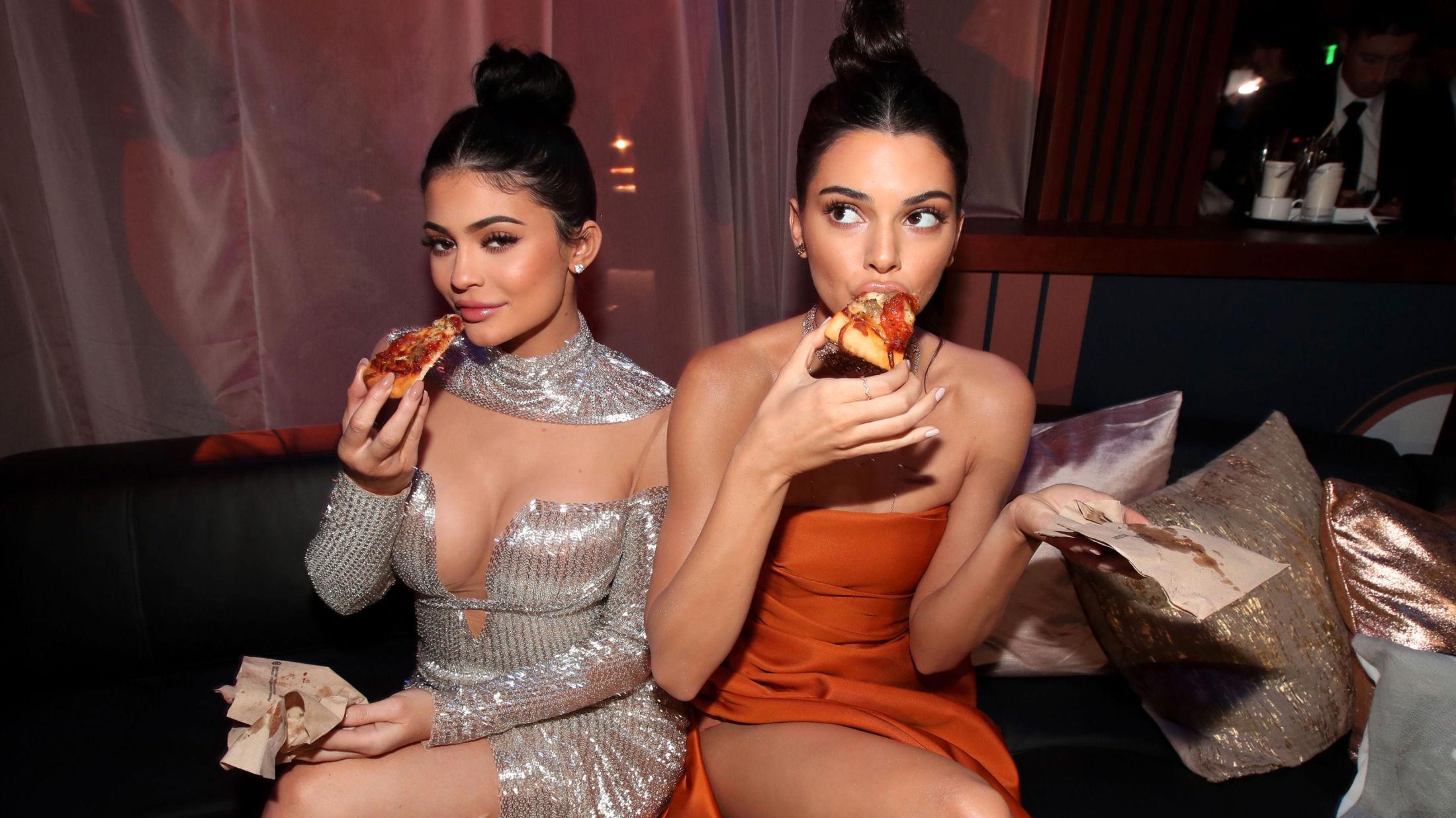 NATTMAT: I løpet av kvelden ble det servert både brus og pizza på etterfesten, og Jenner-søstrene var ikke vanskelige å be. Foto: Getty Images