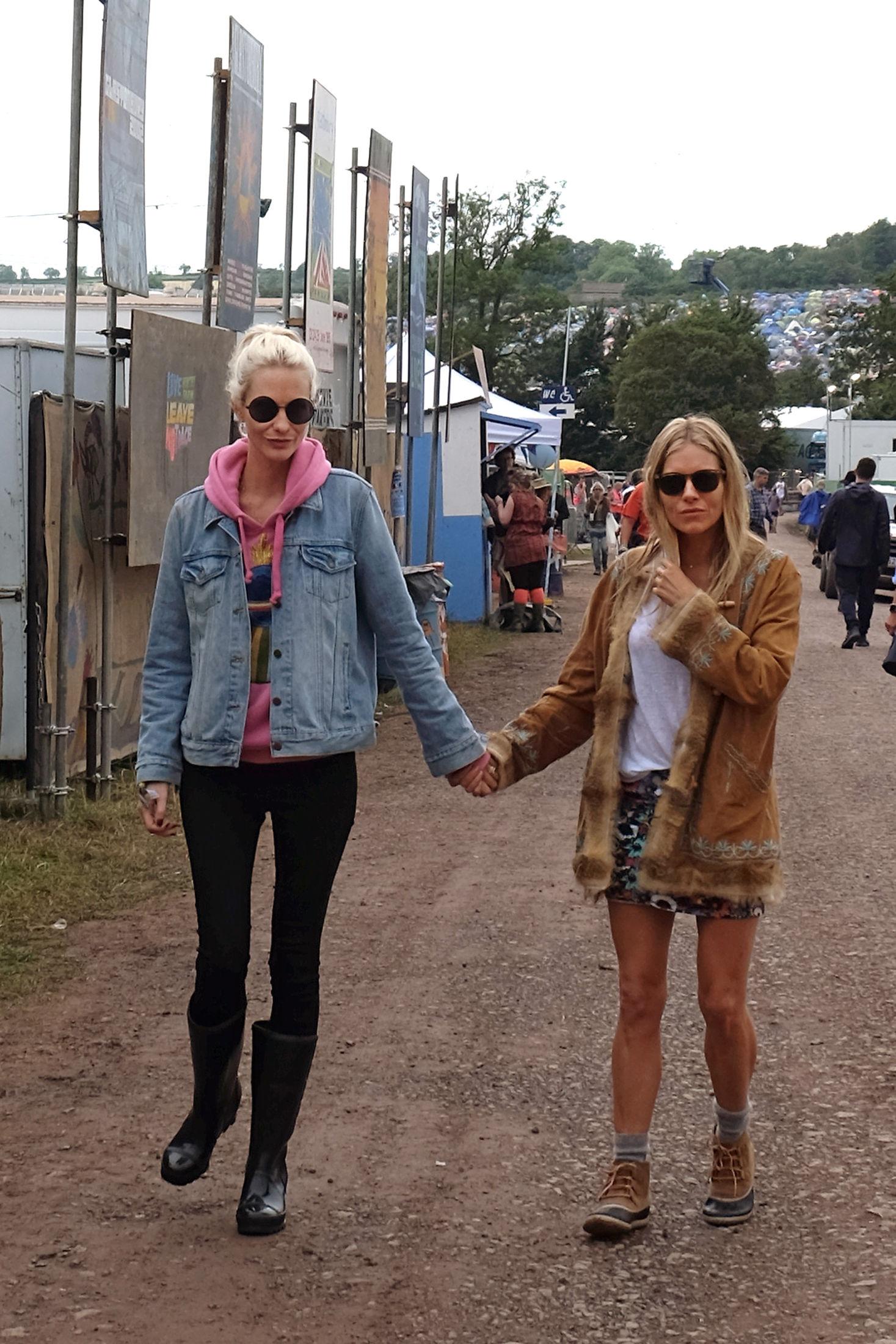 BFFS: Stilikonene Poppy Delevingne og Sienna Miller virker å være faste reisepartnere hvert år på Glastonbury-festivalen. Her er Delevingne er iført rosa hettegenser, tights og jeans, mens Sienna gikk for mønstret skjørt, hvit topp og skinnjakke. Foto: Getty Images
