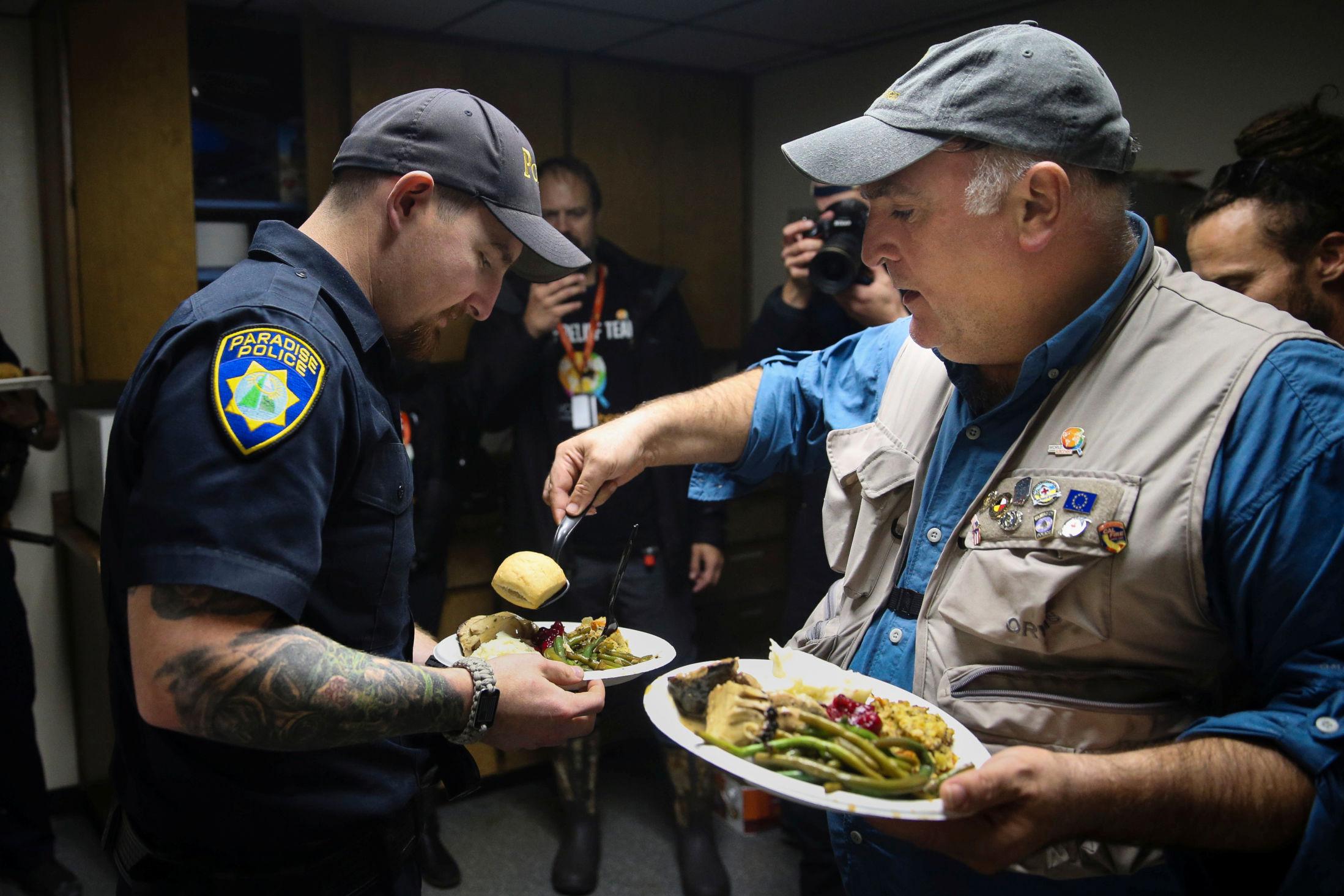 JOBBER FRIVILLIG: Kokk og stifter av organisasjonen World Central Kitchen, José Andrés, serverer Thanksgiving-middag til en politibetjent i Paradise i California i november i år. Foto: Elijah Nouvelage/Reuters