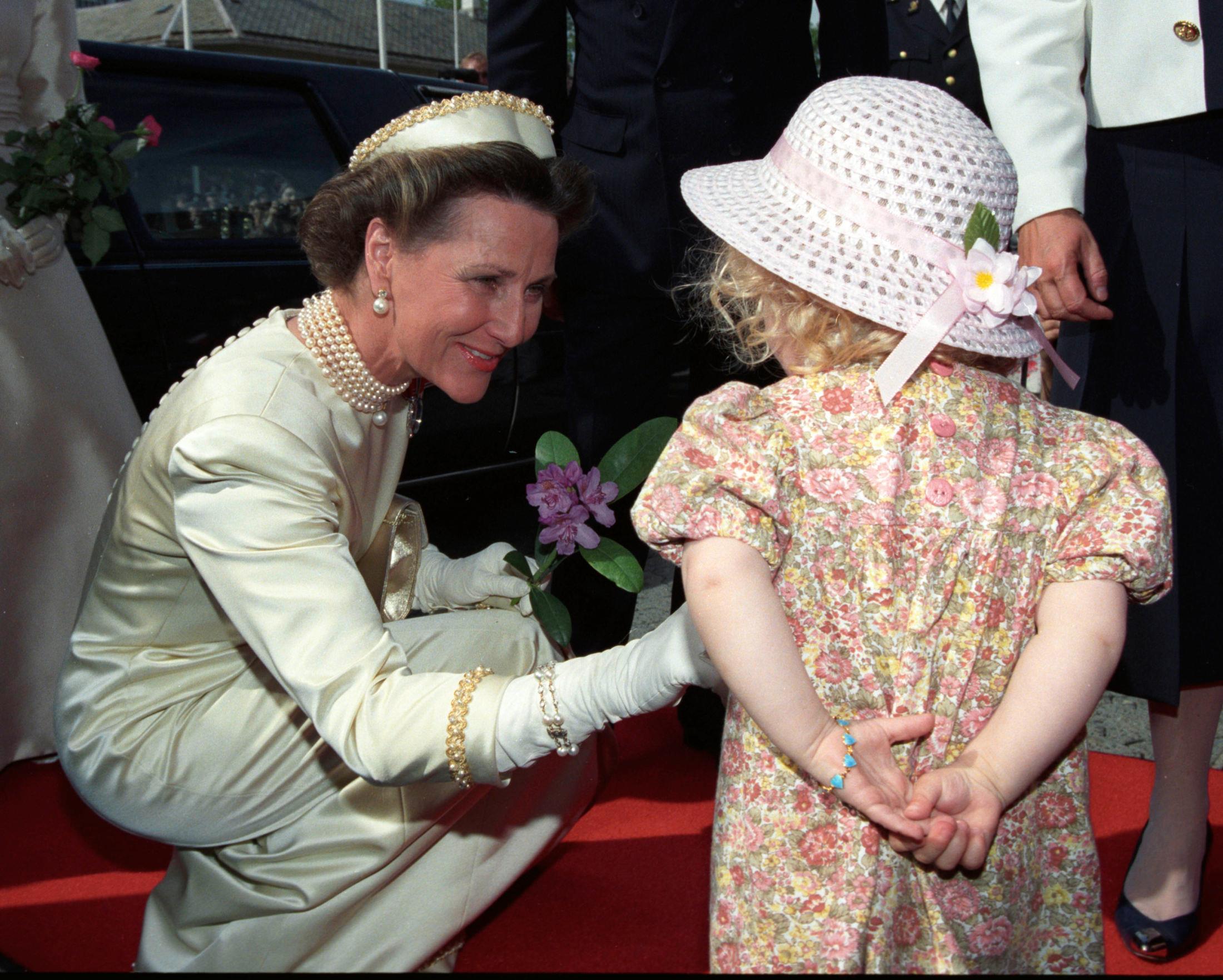 DETALJER: Dronning Sonja blomster fra en liten jente utenfor kirken. Legg merke til at kappen nå er borte - og de mange perledetaljene kommer enda bedre til sin rett. Foto: NTB Scanpix