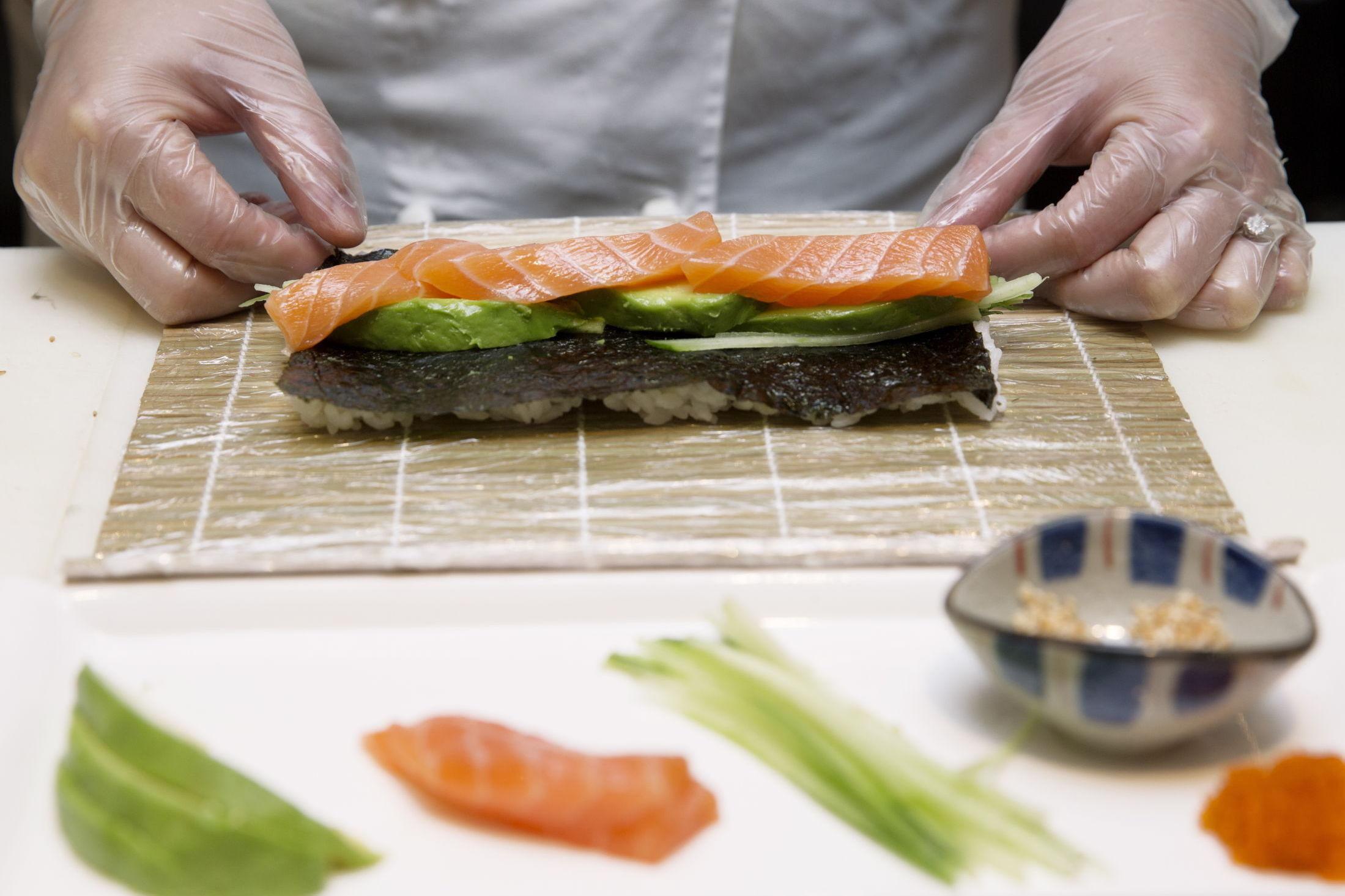 2. Snu siden med ris ned mot sushimatten. Legg agurk, avokado og laks cirka midt på nori-platen.