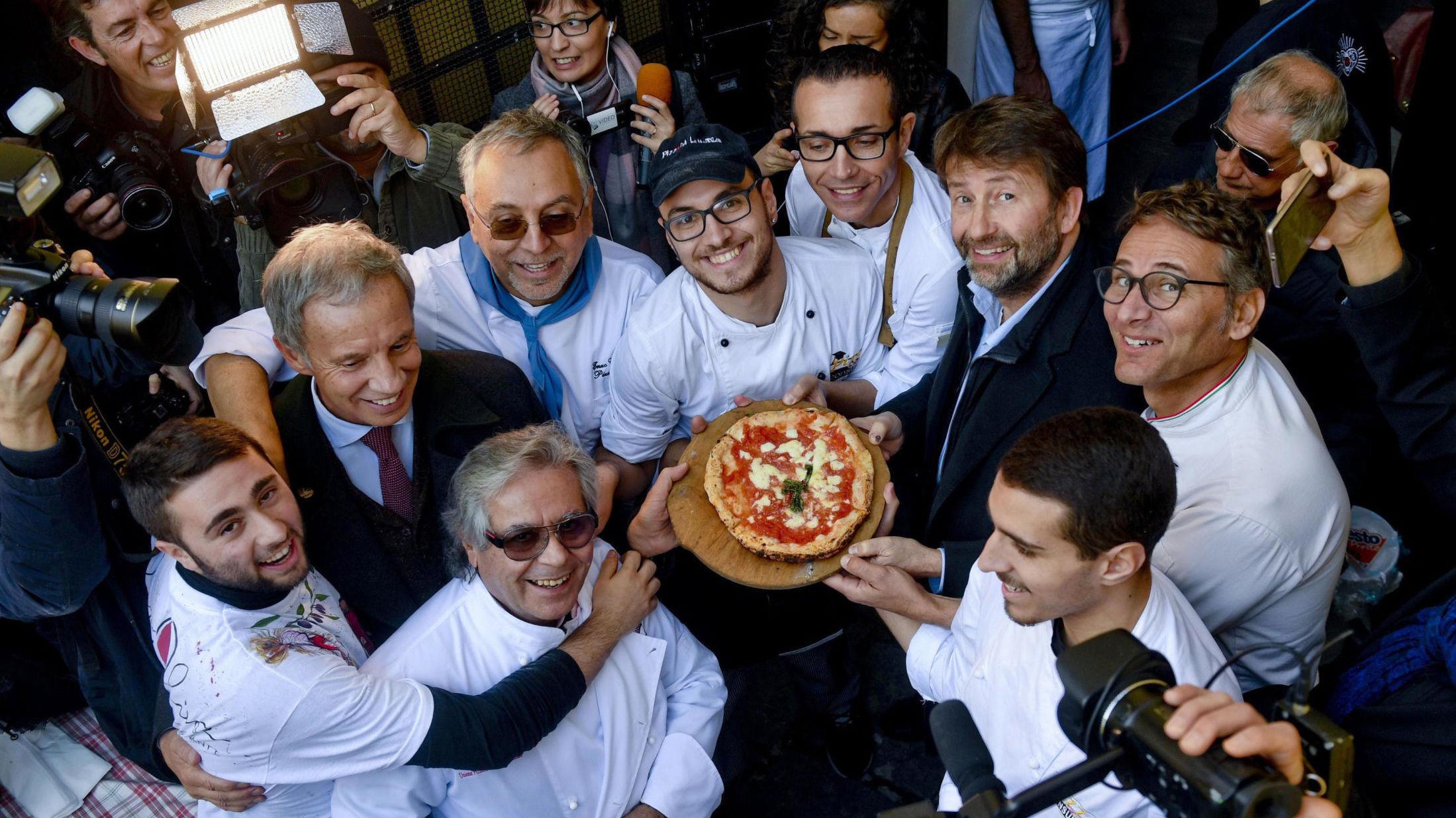 KULTURARVSPIZZA: Italias kulturminister Dario Franceschini, andre fra høyre, holder en pizza bakt i den første steinovnen som ble brukt i 1889 til å lage den første pizza margaritaen i Napoli. Napolis pizzatradisjon har blitt lagt til i UNESCOs liste over immateriell kulturarv. Foto: Ciro Fusco/ANSA Via AP/NTB scanpix