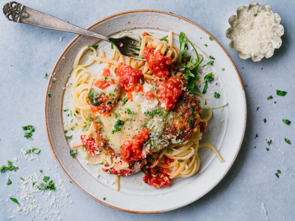 Gratinerad parmesankyckling med tomatsås serverad med nykokt spaghetti och färsk basilika.