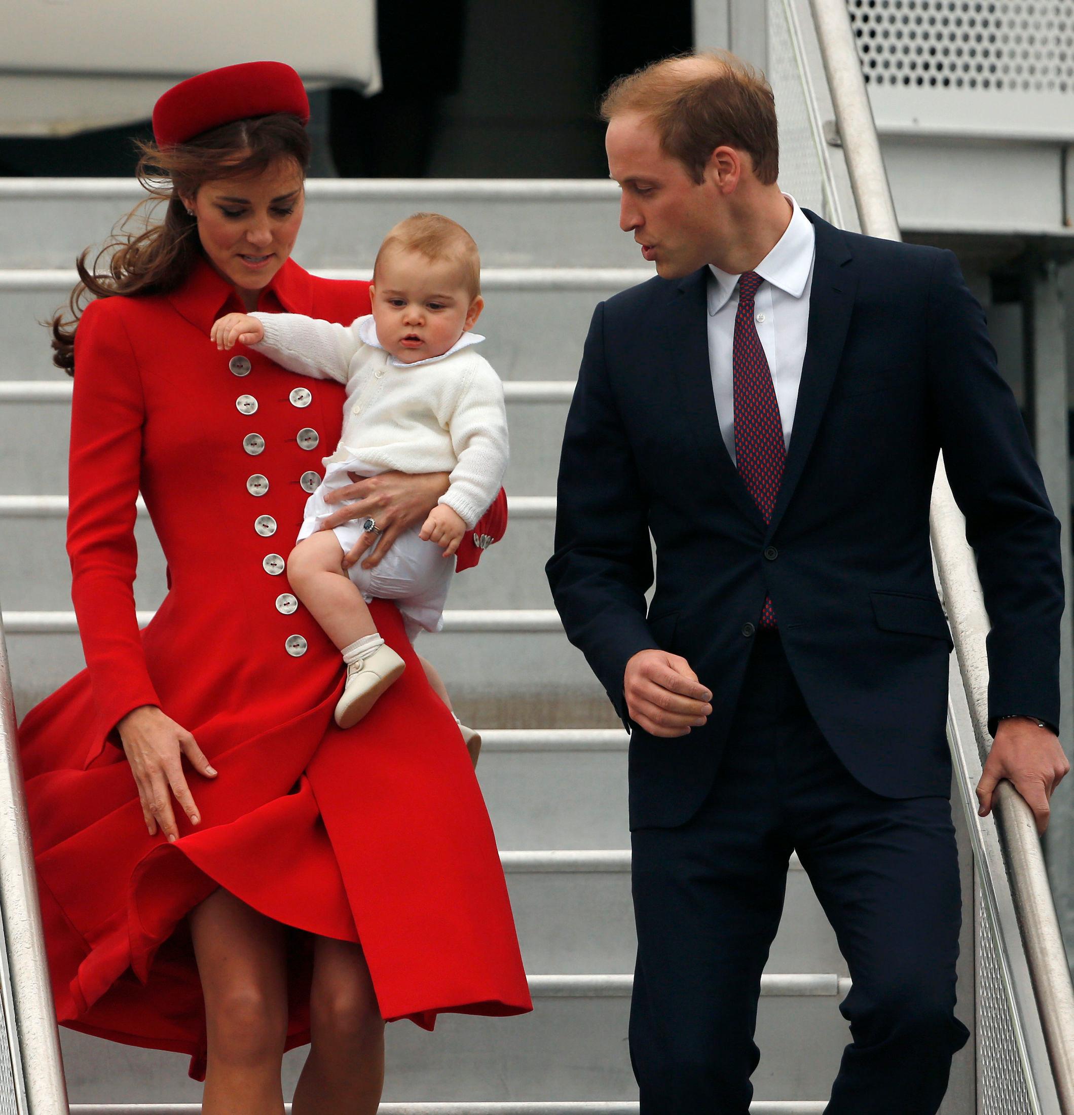 ELEGANT ELLER PIKKOLO?: Kate i en rød kåpe fra Cathrine Walker og matchende hatt. Her ankommer hun New Zealand med sønnen George og prins William. Foto: Reuters