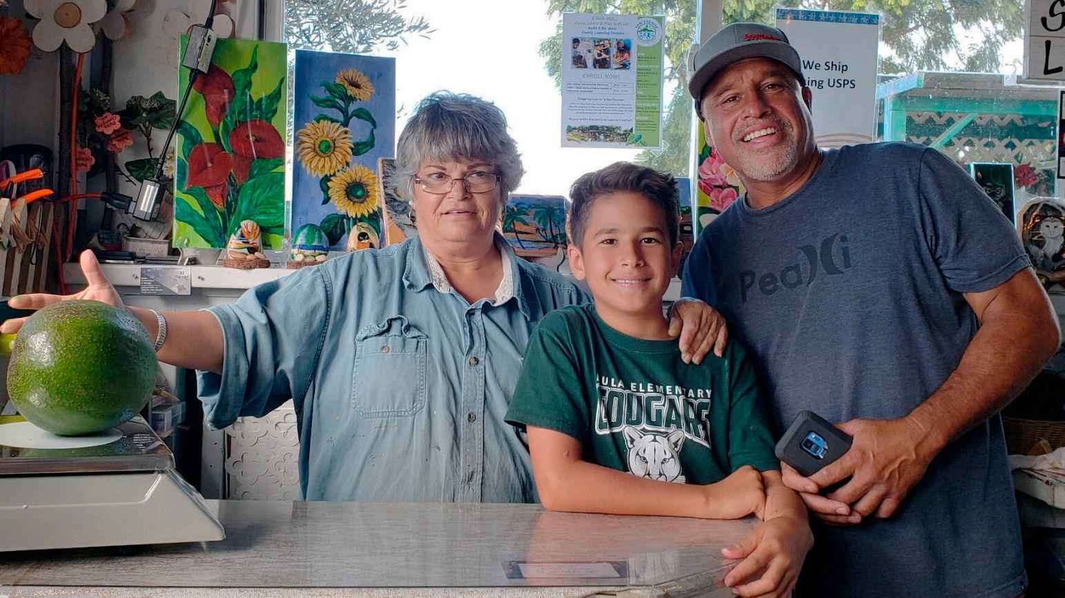 AVOKADOREKORD: Juliane Pokini, sønnen Lo'ihi Pokini og faren Mark Poknin har dyrket frem verdens største avokado i sin egen hage på Maui. Foto: AP