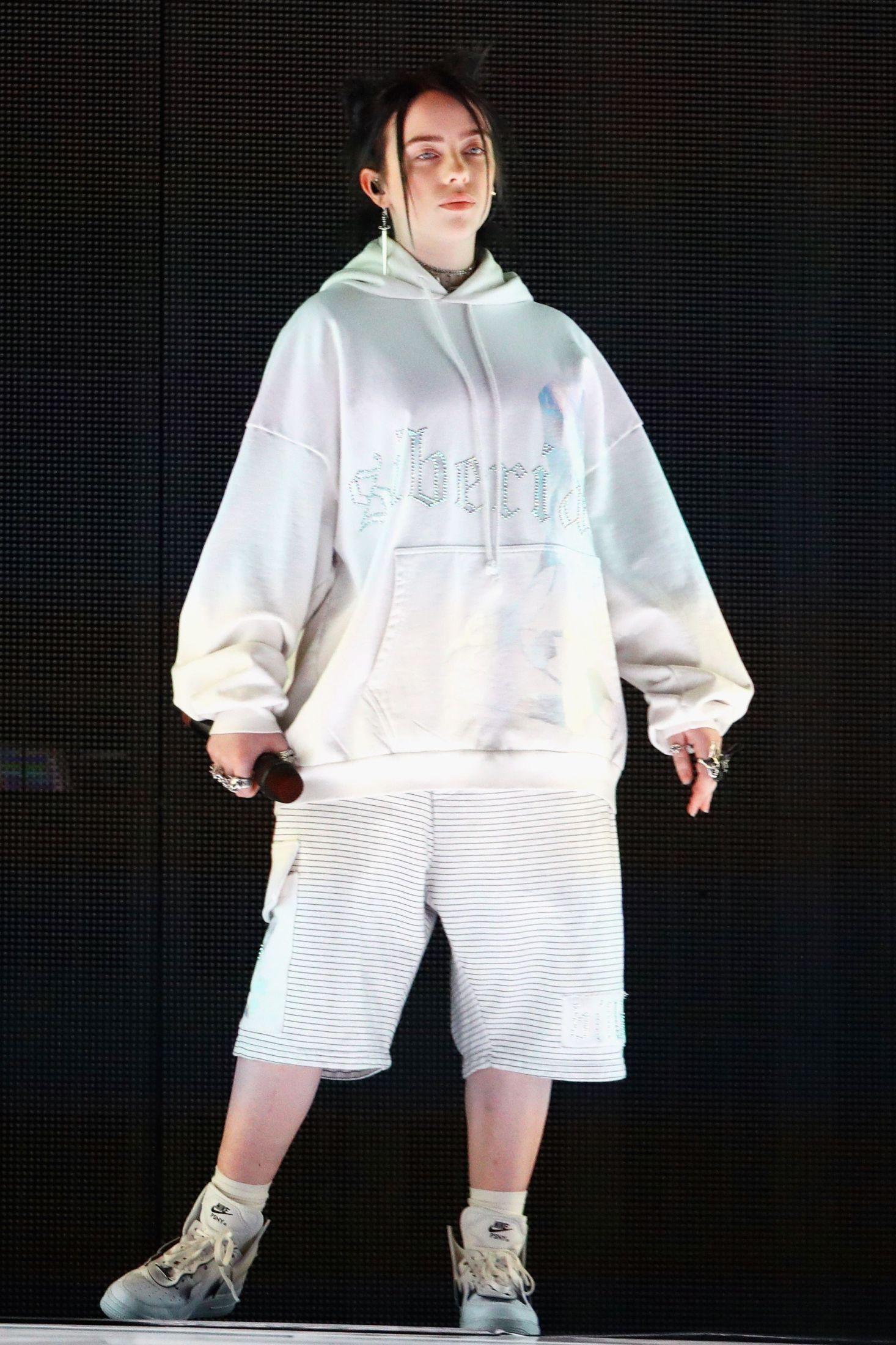 OVERSIZED: Billie Eilish på scenen i en hvit hettegenser og shorts. Foto: AFP