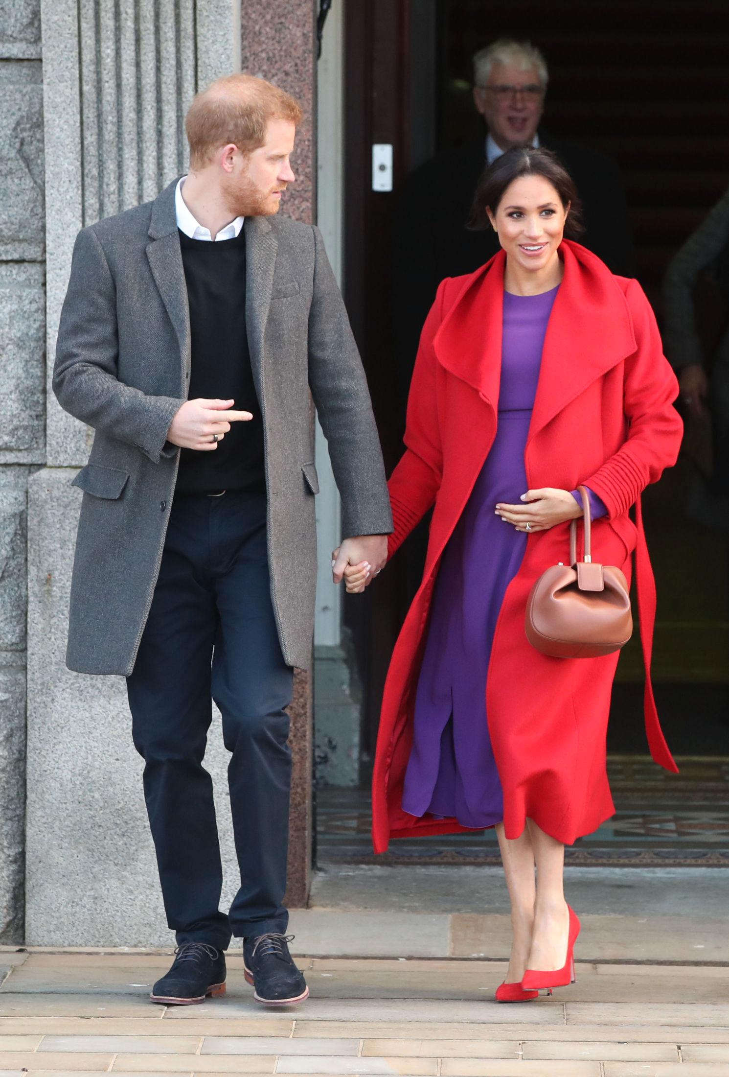 OVERRASKET: Meghan hadde på seg en rød kåpe og matchende pumps, og en lilla knelang kjole. Her var hun og ektemannen prins Harry på årets første oppdrag tidlig i januar. Hertuginnen var gravid i sjette måned. Denne kjolen har hun også brukt ved en annen anledning i år. Foto: Reuters.