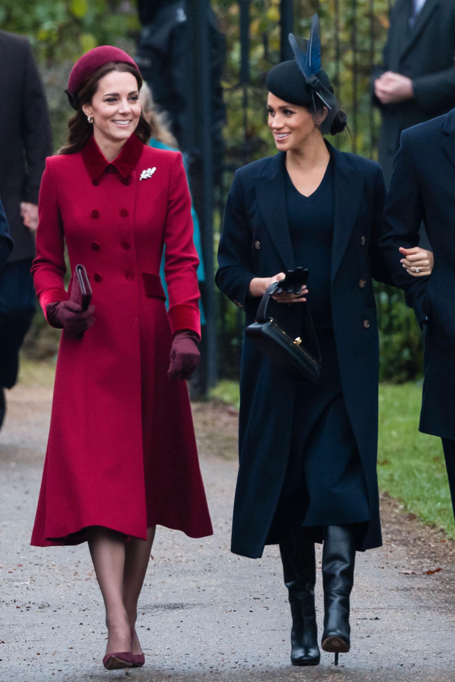 ELEGANTE: Hertuginne Kate gikk for et festlig antrekk i rødt, mens Meghan hadde på seg et mørkeblått antrekk og sorte sko fra Victoria Beckham. Foto: Getty Images