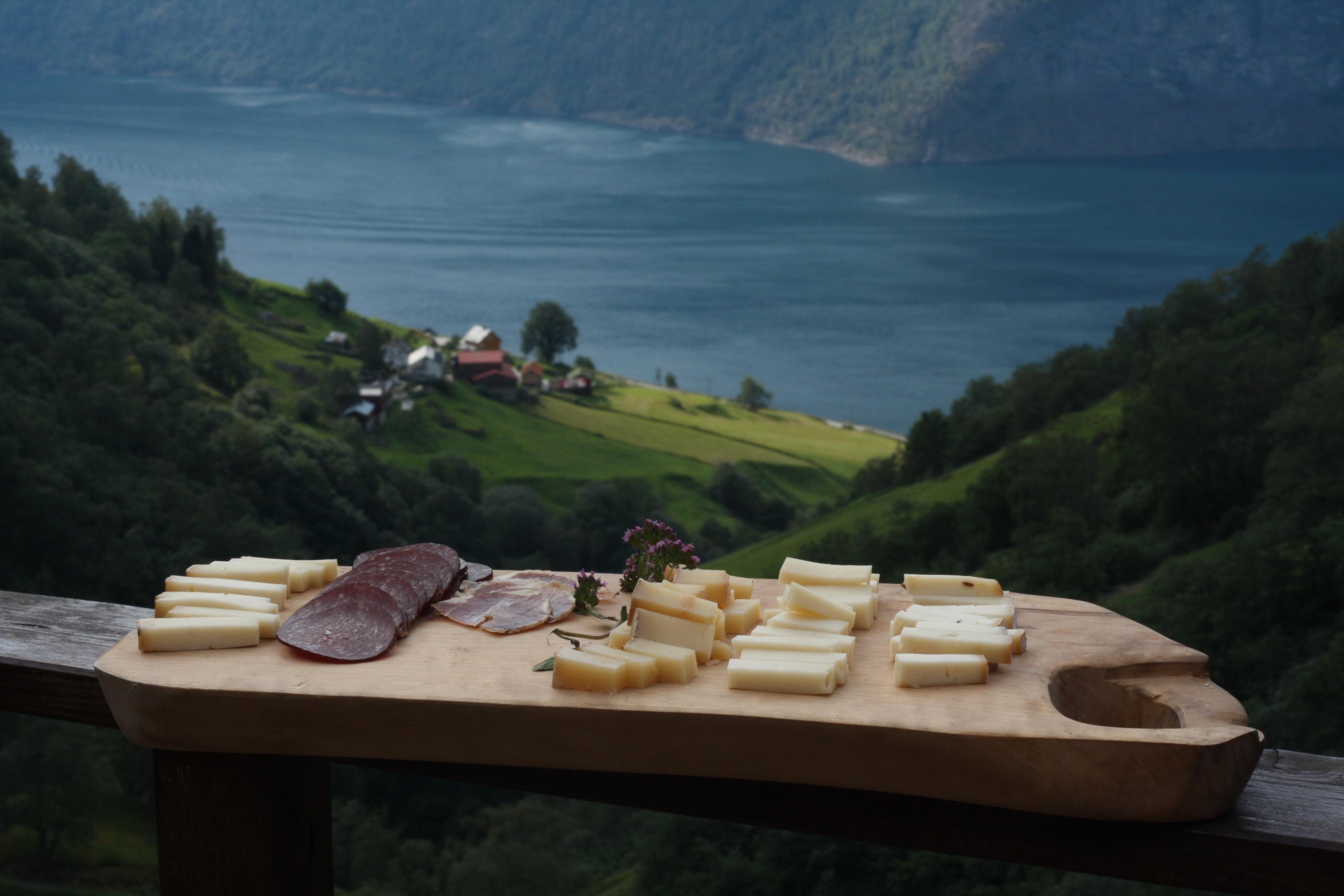 Et brett med geitost fra Skjerdal Stølsysteri med et bakteppe av utsikt fra Skjerdal i Sogn, hvor osten ystes av melk fra egne geiter. 